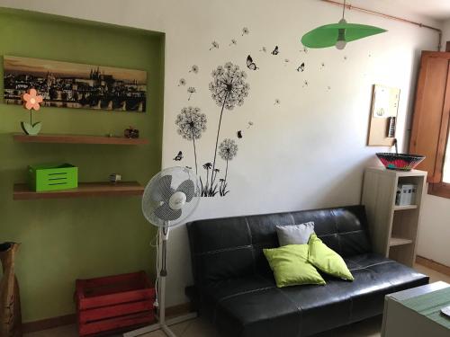 a living room with a black couch and dandelions on the wall at Casa Mojito in Sassari
