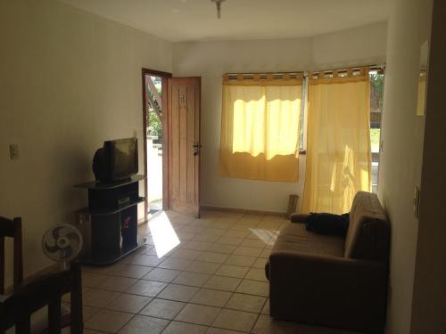 a living room with a couch and a tv at Residence Paraíso in Porto Seguro