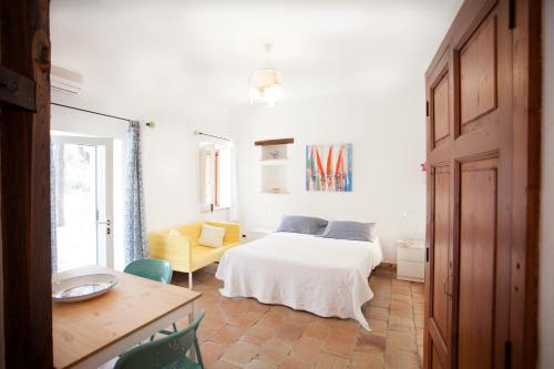 Villaggio Placido في تاورمينا: غرفة نوم بسرير ابيض وكرسي اصفر