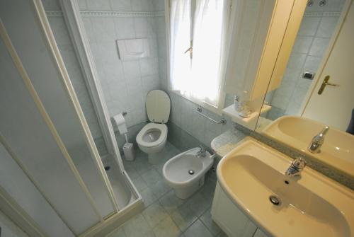 a bathroom with a toilet and a sink and a shower at Villetta Vela in Lignano Sabbiadoro