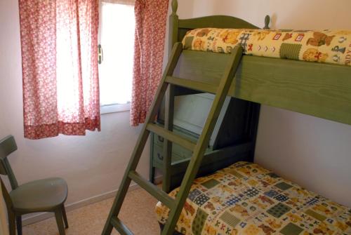 a bunk bed with a ladder and a chair in a room at Villetta Vela in Lignano Sabbiadoro