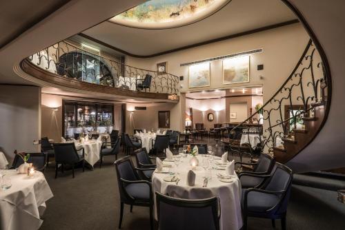 a restaurant with white tables and chairs and a staircase at Hotel Nassauer Hof in Wiesbaden