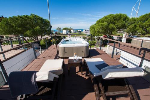 a balcony with a hot tub and tables and chairs at Floating Sea Houses MARINA LUX in Portorož
