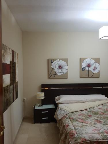 um quarto com uma cama e duas flores na parede em Apartamento Eduardo Dato em Sevilha