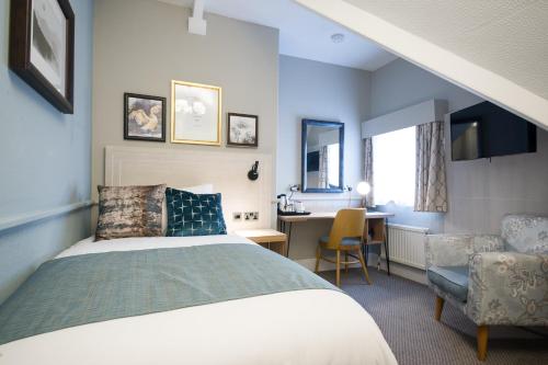 a bedroom with a bed and a desk and a chair at The Swan Inn by Innkeeper's Collection in Horning