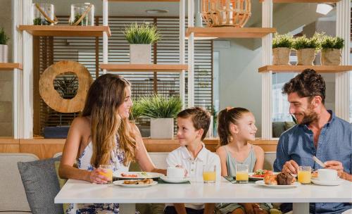 a family sitting at a table eating food at Club del Sol Aparthotel in Port de Pollensa