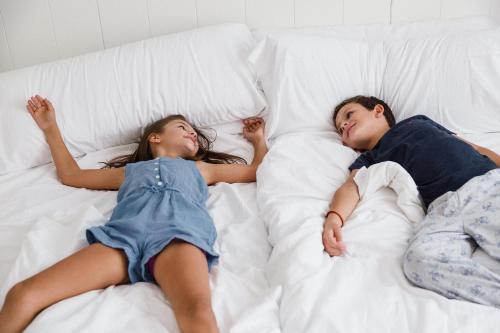 two young children laying on a bed at Club del Sol Aparthotel in Port de Pollensa