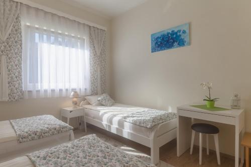 a bedroom with two beds and a table and a window at Apartment Snježana in Slunj