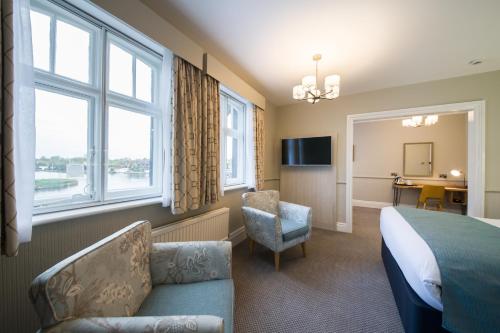 a hotel room with a bed and a couch and windows at The Swan Inn by Innkeeper's Collection in Horning