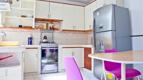 a kitchen with pink chairs and a table and a refrigerator at Le Prince Apart Tacna in Tacna