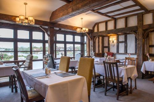 a dining room with tables and chairs and windows at The Swan Inn by Innkeeper's Collection in Horning