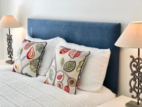 a bed with four pillows and a blue head board at Westlake Apartments in Peterborough