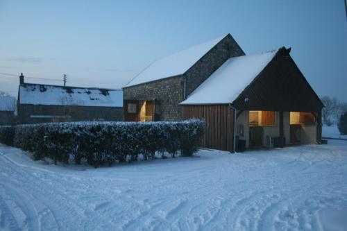 a barn covered in snow in front of a building at Herbages de Beauvais in Orgères-la-Roche