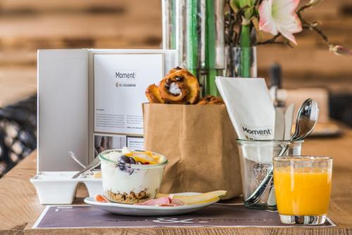 a table with a plate of food and a bag of orange juice at Apart! & Moment! in De Haan