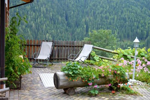 two chairs and flowers on a patio with a view at Kellnerhof in Nova Levante