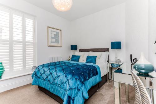 a bedroom with a bed and a desk with a blue comforter at 3, Gainsborough House in Cheltenham