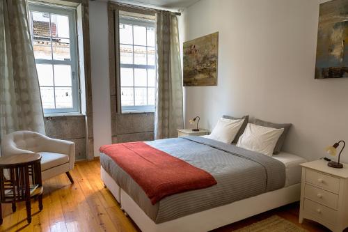 een slaapkamer met een bed en een stoel en 2 ramen bij Casa da Oliveira in Porto