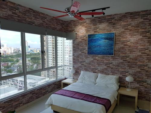 a bedroom with a brick wall and a bed with a ceiling fan at Garden Apartment at Zenith in Petaling Jaya