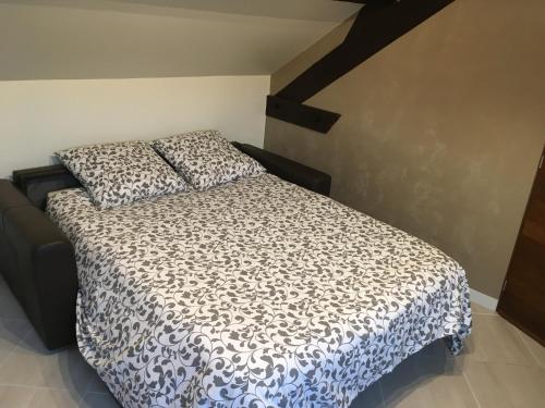 a bedroom with a bed with a black and white comforter at Appart Hôtel l'Orchidée in Morangis