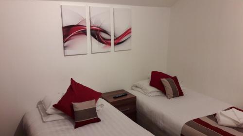 two beds in a room with paintings on the wall at Alexandra Guest House in Hemel Hempstead