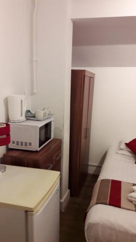 a small room with a microwave and a bed at Alexandra Guest House in Hemel Hempstead