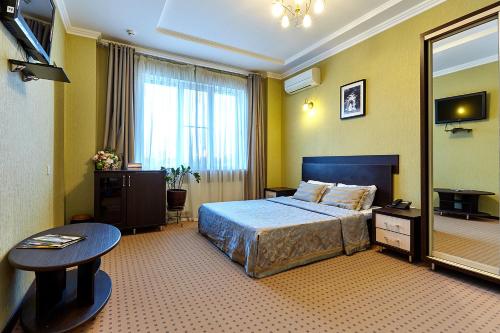 1 dormitorio con cama, mesa y espejo en Iceberg Hotel, en Krasnodar