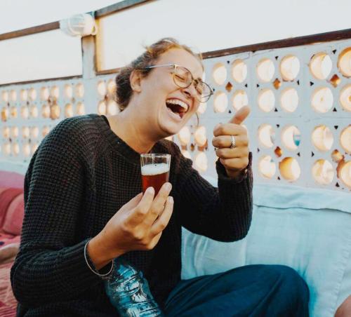 a woman giving a thumbs up while holding a glass of beer at The Madrassa Hostel in Marrakech