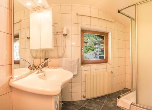 ein Bad mit einem Waschbecken, einem Spiegel und einer Dusche in der Unterkunft Haus Sonnenseit'n in Neustift im Stubaital