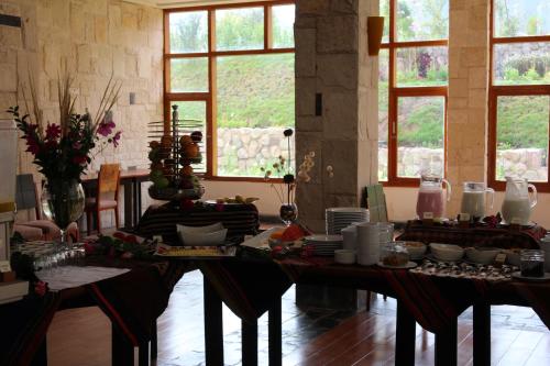 a dining room with a table with food on it at Taypikala Deluxe Valle Sagrado in Urubamba