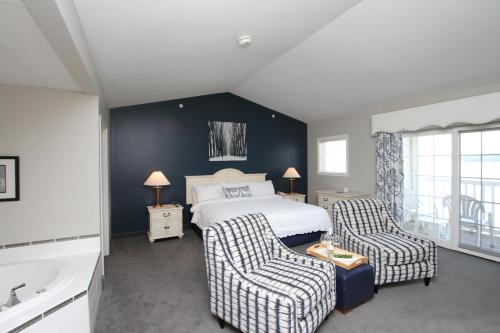 a bedroom with a bed and two chairs and a tub at Bay Pointe Inn in Orangeville