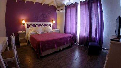 a bedroom with a large bed with purple curtains at Hostería Magnolia in Villa Gesell