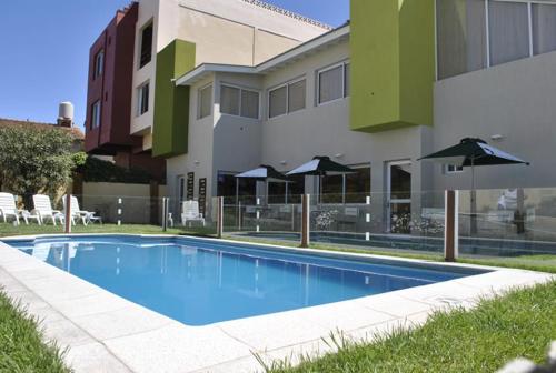 a swimming pool with umbrellas in front of a building at Hostería Magnolia in Villa Gesell