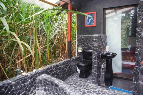 a bathroom with a black toilet in a stone wall at The Secret Buddha in Medellín