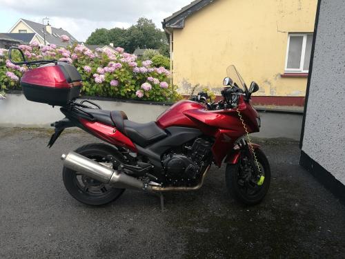 a red motorcycle parked next to a wall with flowers at Assaroe House in Ballyshannon
