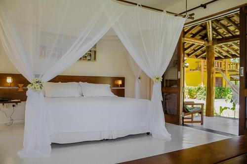 a bedroom with a white bed with a canopy at Villa dos Corais in Morro de São Paulo