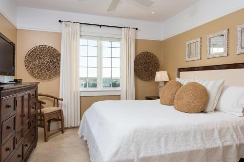 a bedroom with a white bed and a window at The Regent Grand in Grace Bay