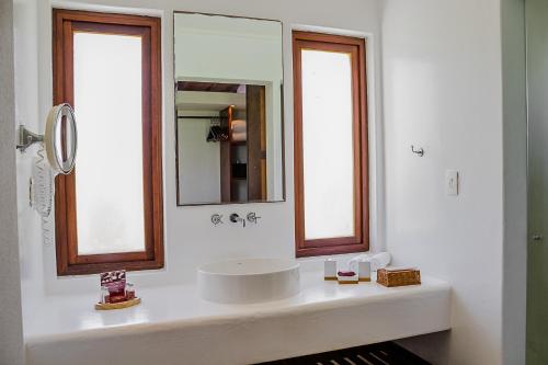 a white bathroom with a sink and a mirror at Villa dos Corais in Morro de São Paulo