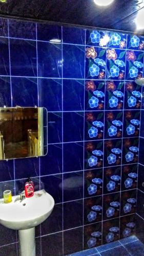 a blue tiled bathroom with a sink and a mirror at Colibri Home in Kutaisi
