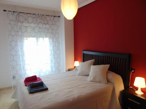 Un dormitorio con una cama con paredes rojas y una ventana en Vivienda Turistica Bufer, en Úbeda