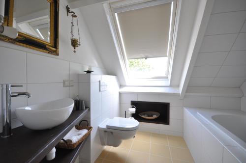 een badkamer met een wastafel, een toilet en een raam bij B&B Nieuwe Brug in Vijfhuizen