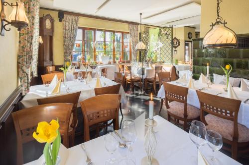 a restaurant with white tables and chairs and windows at Land-gut-Hotel Lohmann in Drensteinfurt