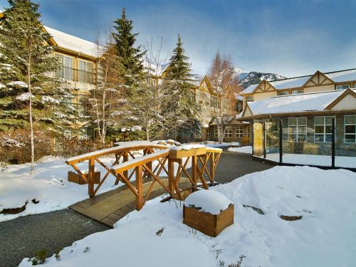 a wooden picnic table in the snow in front of a building at Coast Canmore Hotel & Conference Centre in Canmore