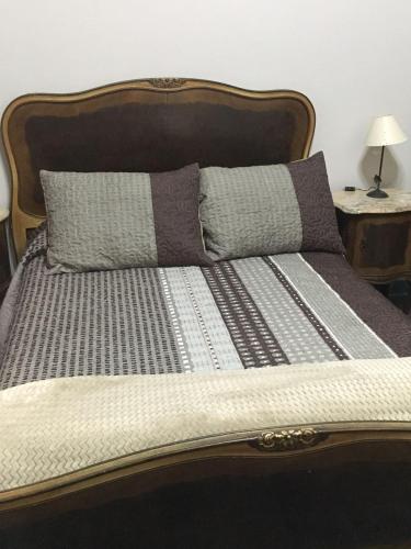 a bed with a wooden headboard and two pillows at Carmine Hotel Apart in Capilla del Señor