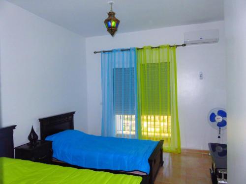 a bedroom with a blue and green bed and a window at Chez Younès Appartement Marina Saidia Ap8 in Saidia 