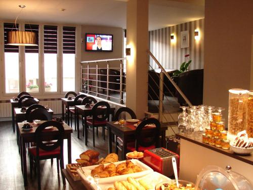 a restaurant with tables and chairs and a counter with food at Logis Hotel - Le Charleston in Le Mans