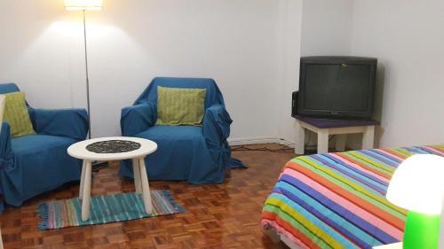 sala de estar con 2 sillas azules y TV en Distrito Palermo Apartment en Buenos Aires
