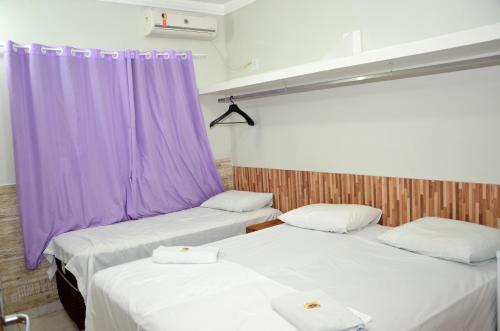 a hotel room with two beds and two lamps at Hotel Cerrado in Goiânia