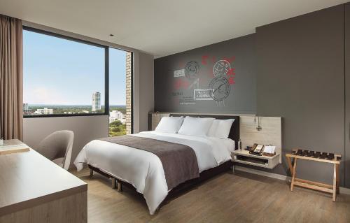 a bedroom with a large bed and a large window at Hotel Sites Montería in Montería