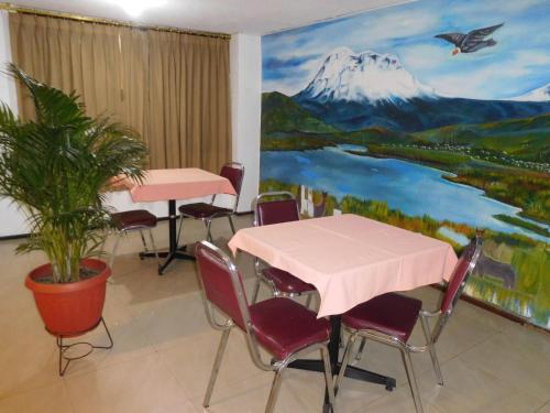 une chambre avec des tables et des chaises et un tableau représentant une montagne dans l'établissement Hostal Alborada Riobamba, à Riobamba