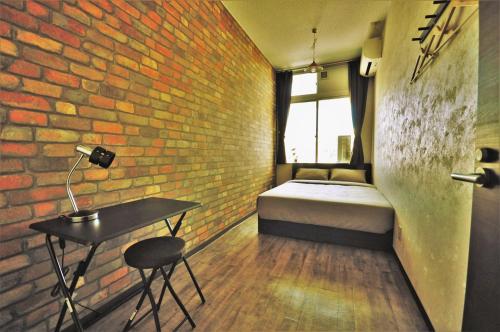 sypialnia z łóżkiem, stołem i ceglaną ścianą w obiekcie My Place w mieście Naha